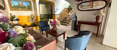 A hotel lobby with a staircase, seating area, and artwork on the walls.