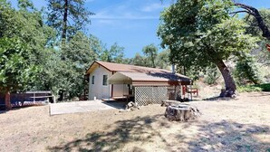 A small house with a wooden deck, surrounded by trees. - Spacious home in Sequoia National Forest (California Hot Springs)