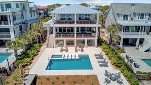 A two-story house with a large swimming pool, multiple decks, and outdoor seating areas. - 712 Ocean Blvd by Avantstay New Construction w/ Pool, Game Zone, Private Beach Access, and Oceanfront Views (Isle of Palms)