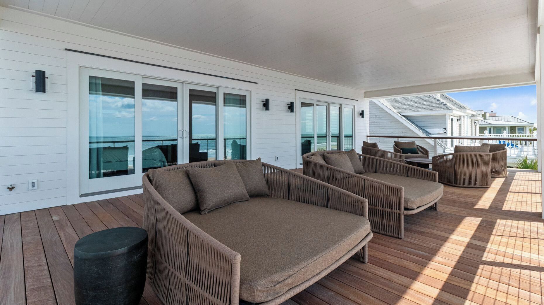 A deck with wicker furniture and glass doors leading to a balcony.