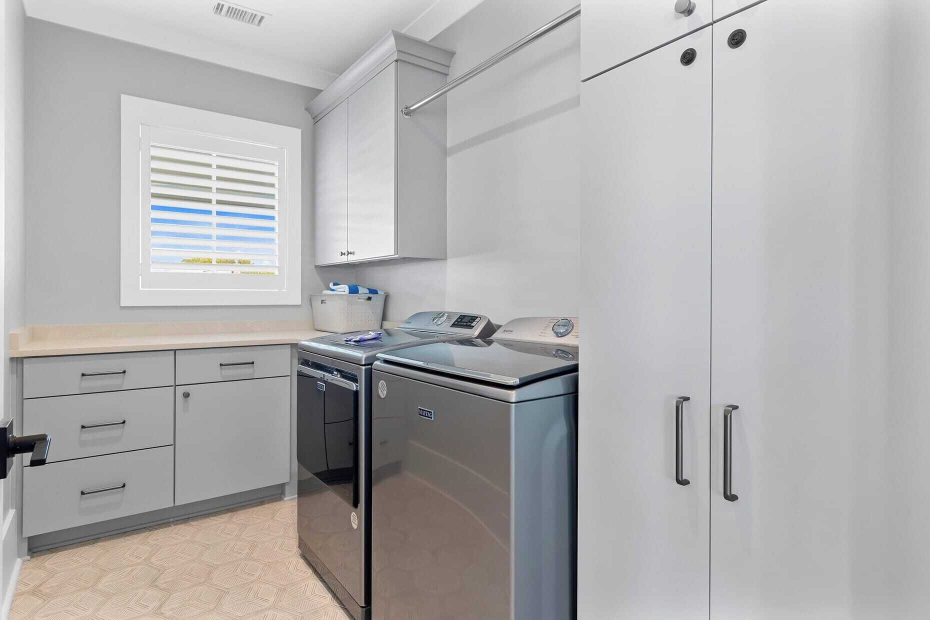 A kitchen with grey cabinets, a built-in dishwasher, and a stainless steel refrigerator.