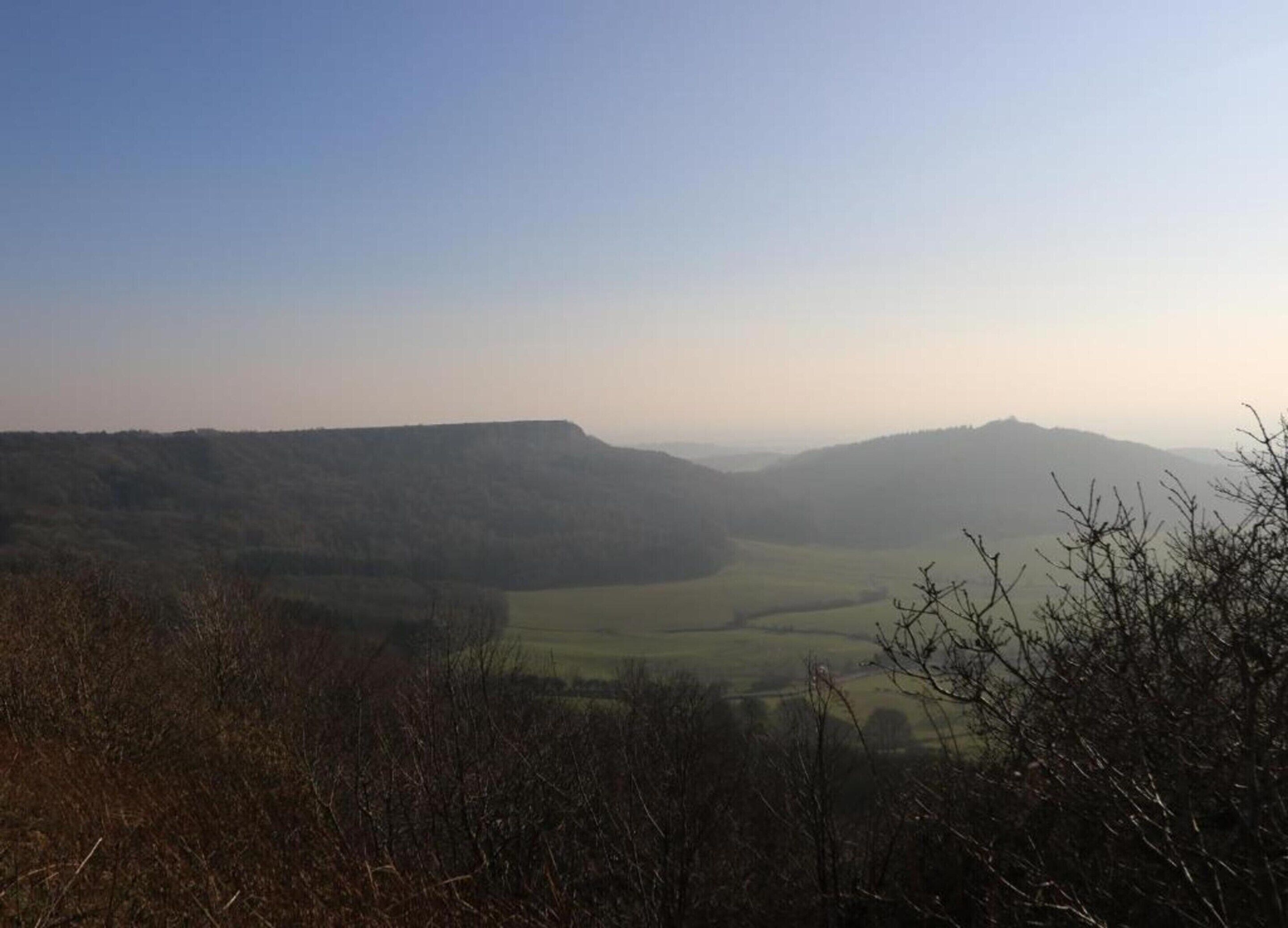 Una vista panoramica di una valle con dolci colline e cielo sereno.