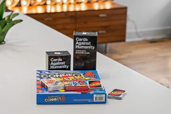 Una mesa con diversos juegos de mesa, incluyendo UNO y Cards Against Humanity.