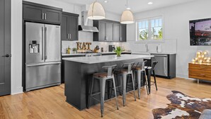 Una cocina moderna con una isla grande, electrodomésticos de acero inoxidable e iluminaci ón colgante.