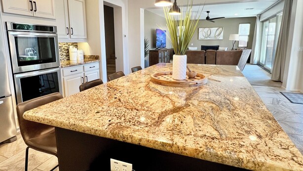 A kitchen with granite countertops, stainless steel appliances, and a central island with a vase and plant. - Spacious 5-bedroom house in fabulous Queen Creek with WiFi, AC (Queen Creek)