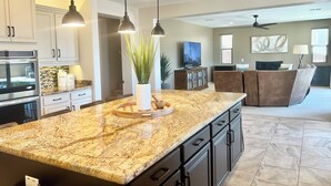 A modern kitchen with granite countertops, dark cabinetry, and pendant lighting. - Spacious 5-bedroom house in fabulous Queen Creek with WiFi, AC (Queen Creek)