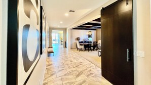 A hallway with a dining area, a dark wooden door, and a patterned floor. - Spacious 5-bedroom house in fabulous Queen Creek with WiFi, AC (Queen Creek)