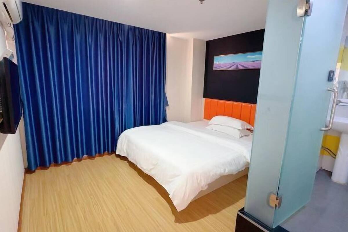 Ein Hotelzimmer mit Bett, Wandfernseher und Badezimmertür.