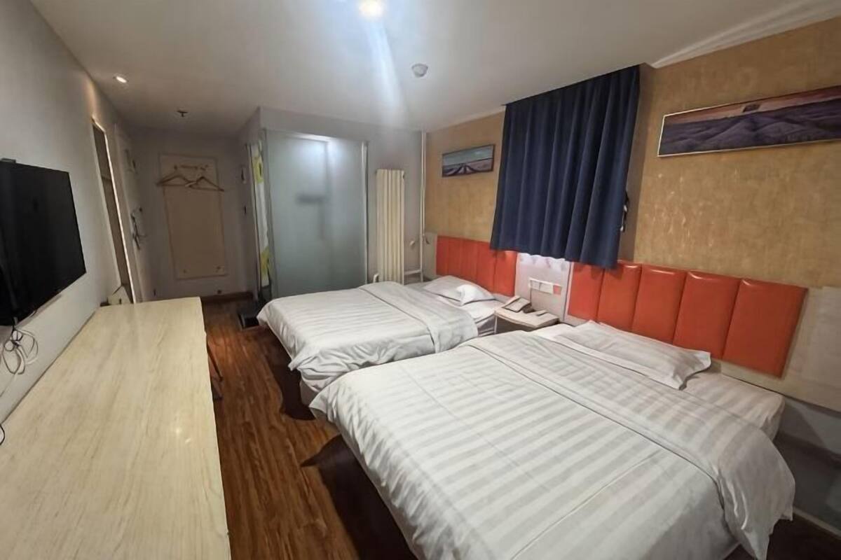 Ein Hotelzimmer mit zwei Betten, einem Schreibtisch, einem Fernseher und einem Badezimmer.