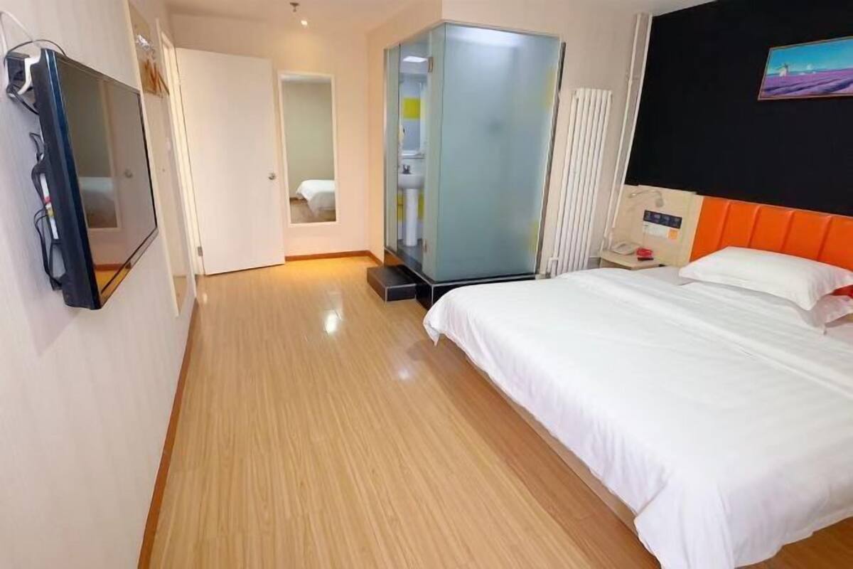 Ein Hotelzimmer mit Bett, Fernseher, Schrank und einem durchgegangenen Tür sichtbar erkennbaren Badezimmer.