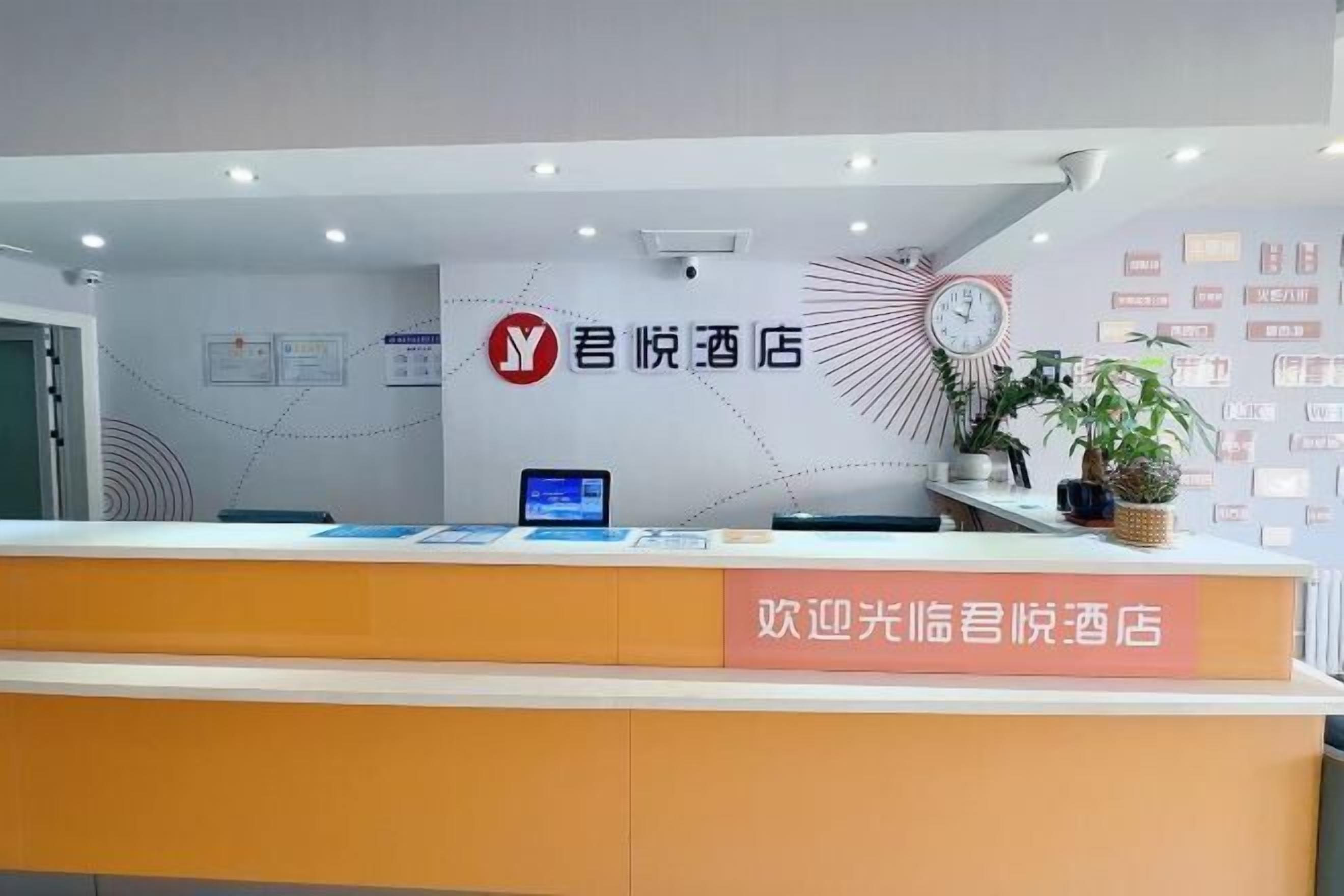 A reception desk with a clock, a digital screen, and a sign welcoming guests to the hotel.