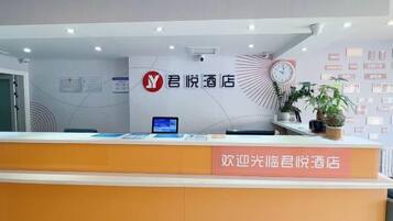 A reception desk with a clock, a digital screen, and a sign welcoming guests to the hotel.