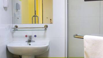 A bathroom with a white sink, a glass shelf above it, and a towel rack.