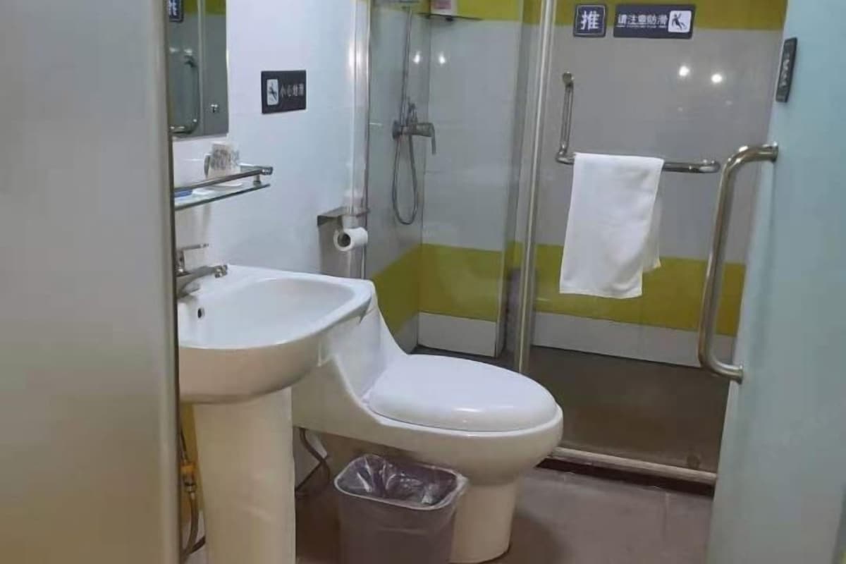 Une salle de bain équipée de toilettes, d’un lavabo et d’une douche à parois en verre.