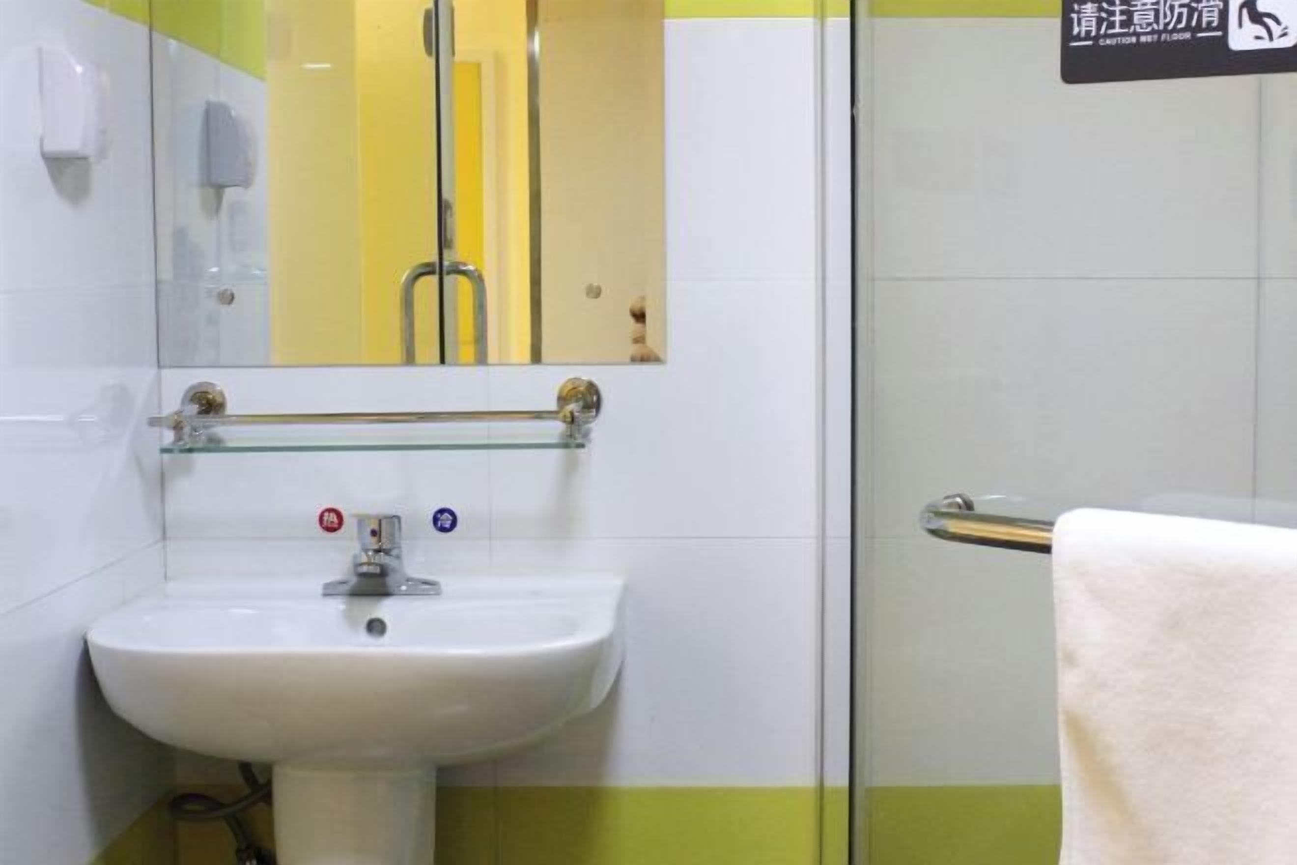 A bathroom with a white sink, a glass shower enclosure, and a towel rack.