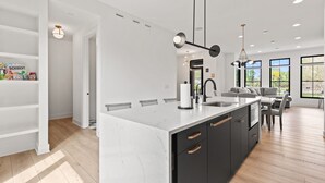 A modern kitchen with a large island, built-in appliances, and pendant lighting.