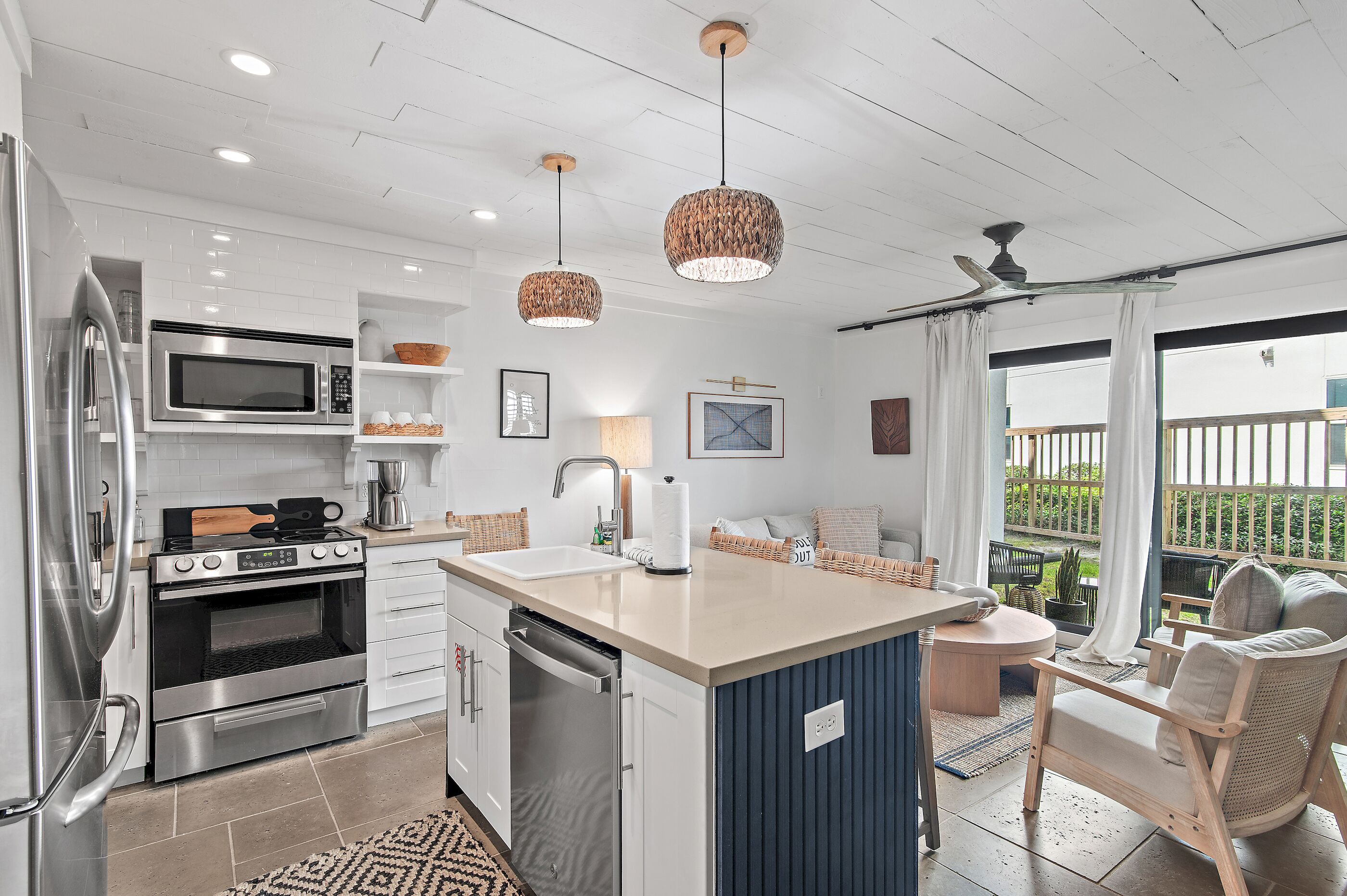 A modern kitchen with stainless steel appliances, a central island, and a dining area with a view.