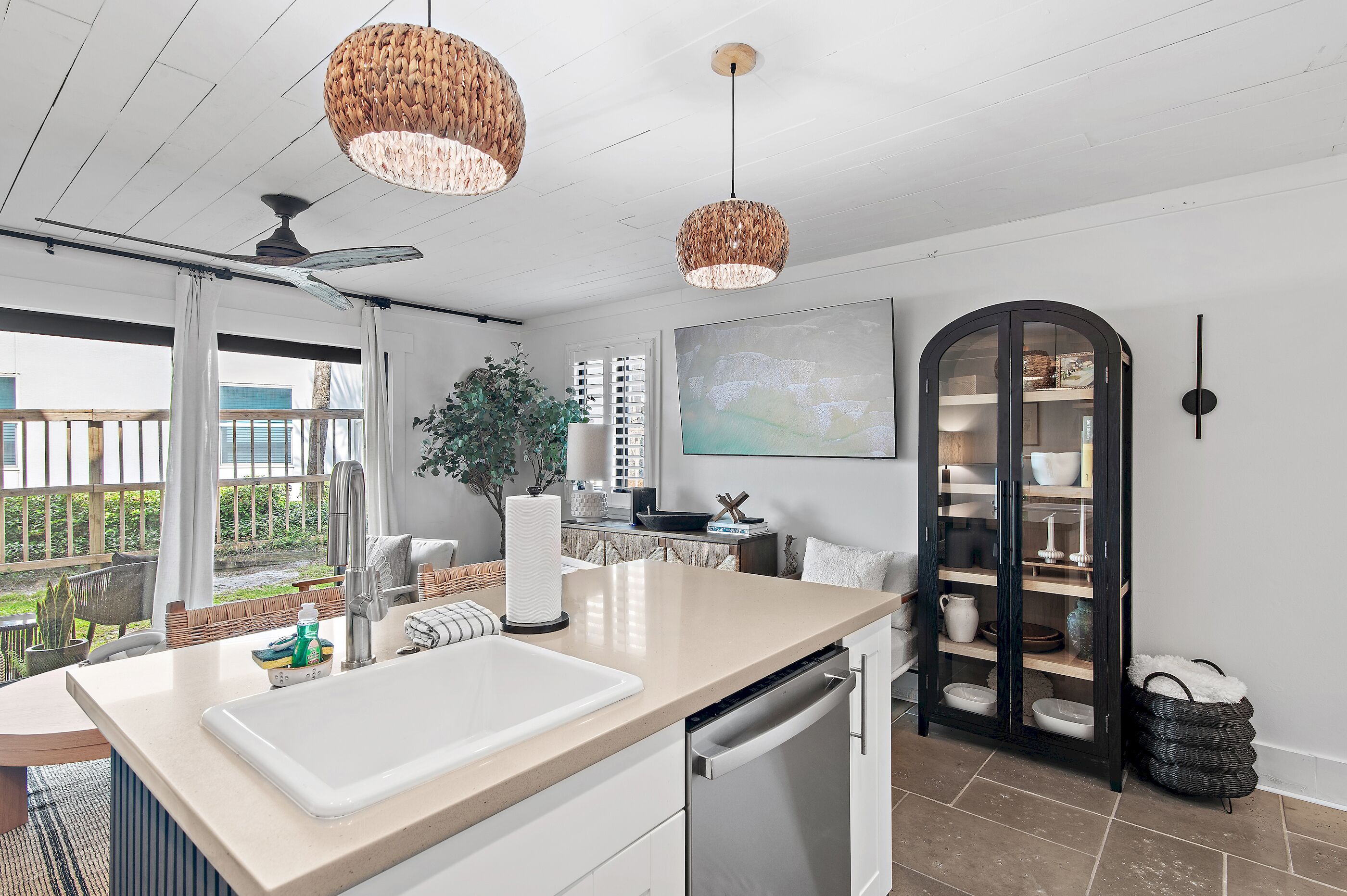 A modern kitchen with a large island, white cabinetry, and a dining area with a view.