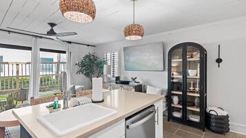 A modern kitchen with a large island, white cabinetry, and a dining area with a view.