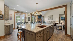 A spacious kitchen with a large island, wooden cabinetry, and a stone fireplace. - Spacious Waterfront Home on Lake Norman With Firepit, Views, and Dock Access (Sherrills Ford)