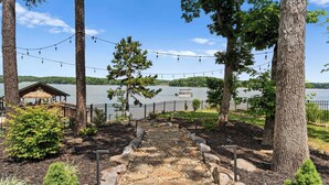A stone pathway leading to a gazebo by a lake, surrounded by trees and a fence. - Spacious Waterfront Home on Lake Norman With Firepit, Views, and Dock Access (Sherrills Ford)