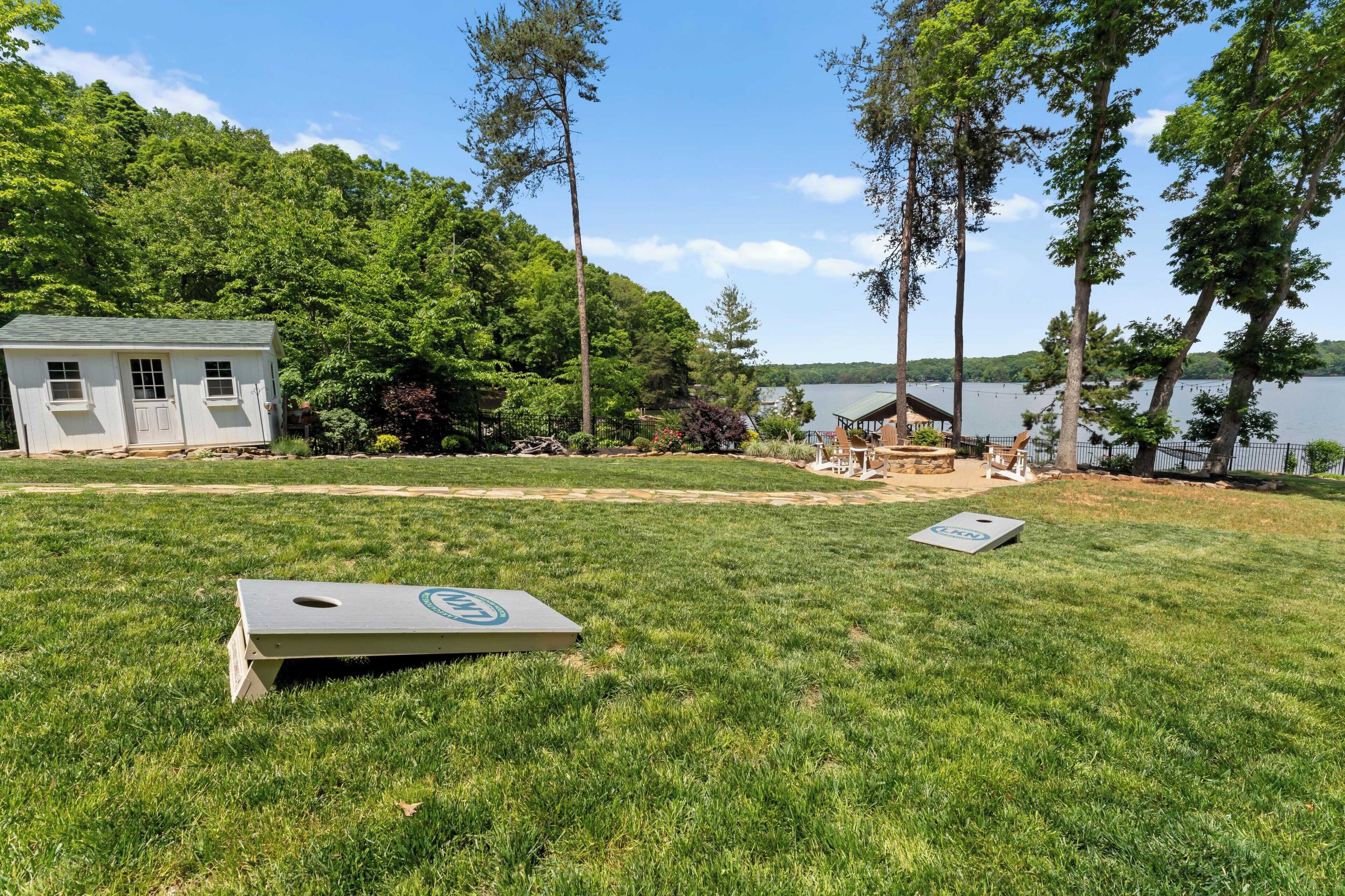 A grassy yard with a small shed, a wooden deck, and a view of a lake.