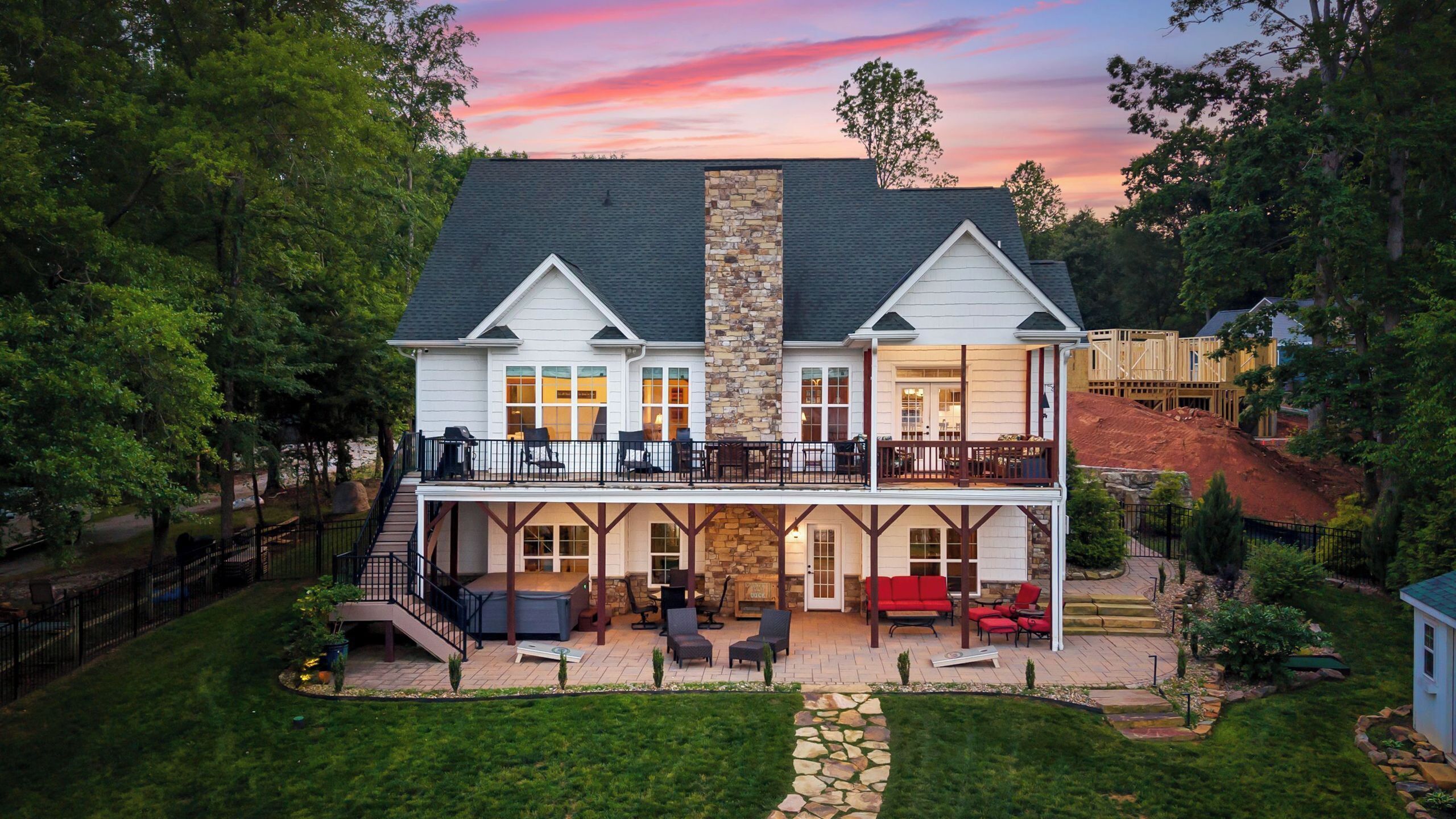 A two-story house with a stone fireplace, a balcony, and a patio with outdoor furniture.