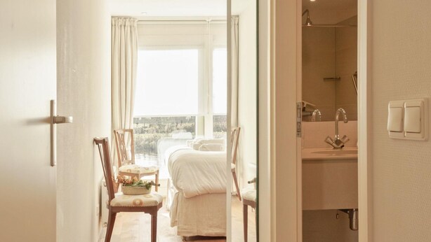 A hotel room with a bed, a chair, a desk, and a view of the city. - Holiday Home in Terherne Near Scenic Friesland (Terherne)