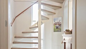 A staircase with wooden steps and a wooden handrail, leading to a door with a framed picture of a cow. - Holiday Home in Terherne Near Scenic Friesland (Terherne)