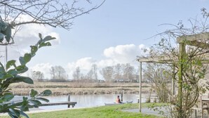 A riverside park with a canoeist, grassy areas, and a wooden structure. - Holiday Home in Terherne Near Scenic Friesland (Terherne)