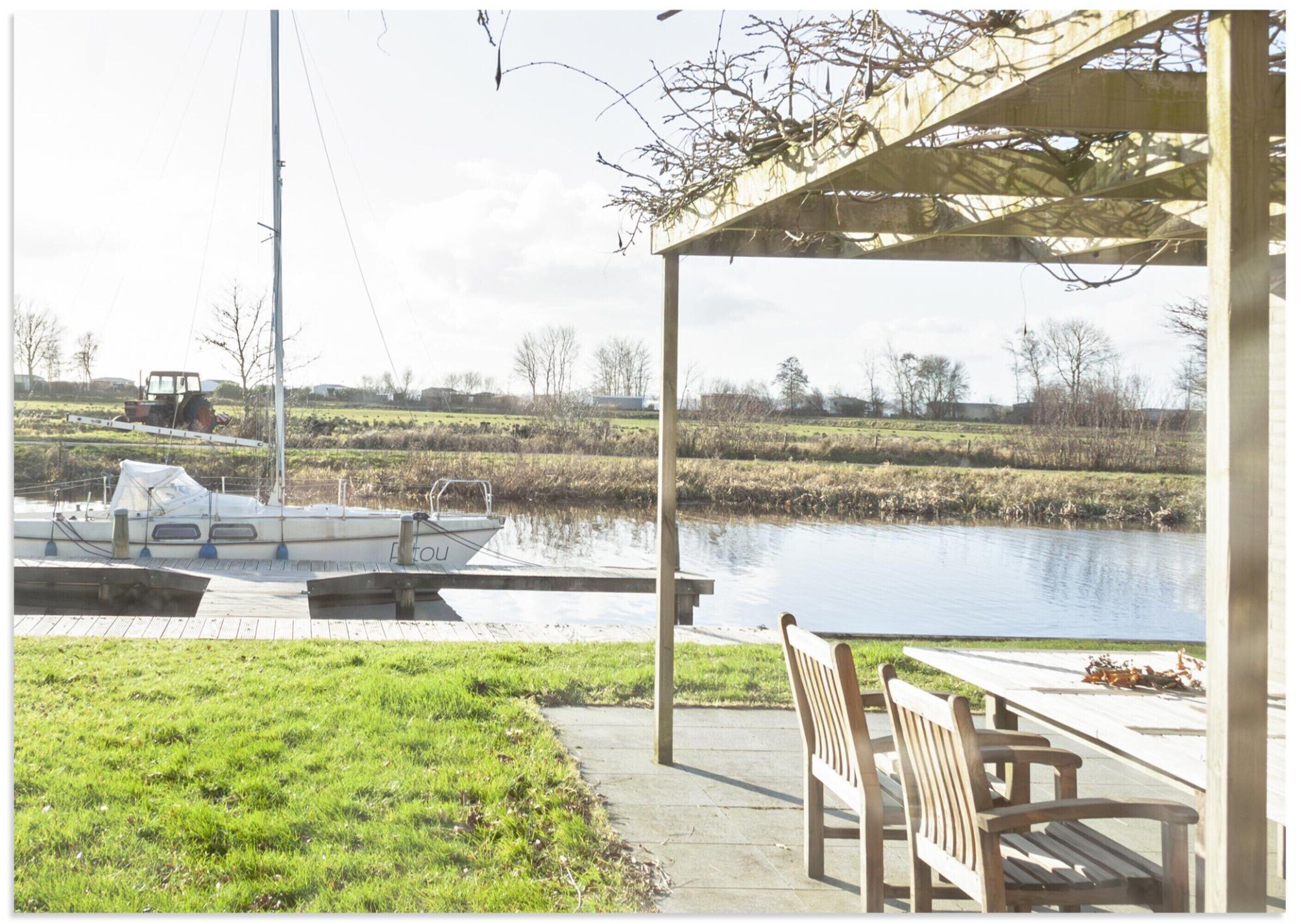 A riverside patio with a covered seating area, a dock with a boat, and a tractor in the background.