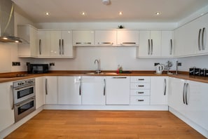 Una cocina moderna con armarios blancos, electrodomésticos de acero inoxidable y encimeras de madera.