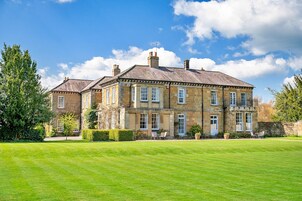 A large stone building with multiple windows and a well-maintained lawn.