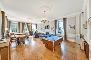 A spacious room with a pool table, dining area, and seating.