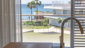 A modern hotel room with a view of the ocean and palm trees.