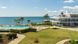 A modern hotel with a pool, palm trees, and a view of the ocean.