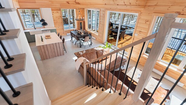 A wooden cabin interior with a dining area, kitchen, and a staircase. - Chamonix Kanata Tremblant (140 Pavillon-Kanata) (Amherst)