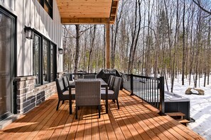 A wooden deck with outdoor furniture, a hot tub, and a view of a snowy forest. - Chamonix Kanata Tremblant (140 Pavillon-Kanata) (Amherst)
