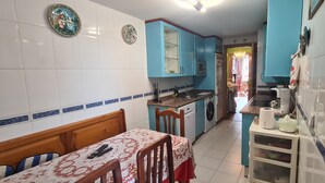 Una cocina con armarios azules, una mesa de comedor con sillas y un refrigerador.