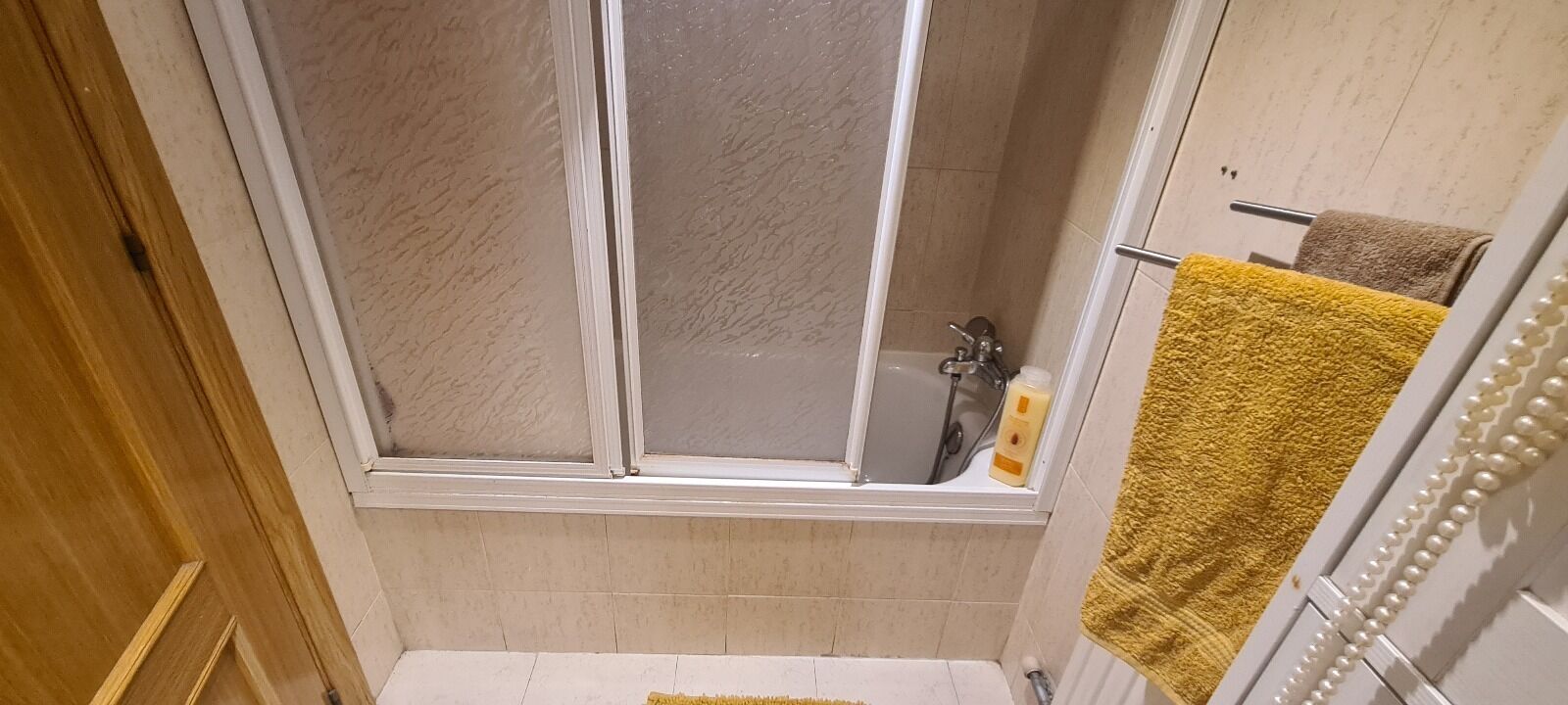A bathroom with a shower, a bathtub, and a towel rack.