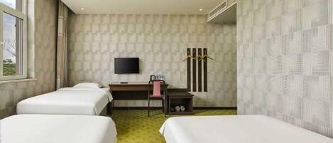 A hotel room with two beds, a desk, a chair, a TV, and a window.