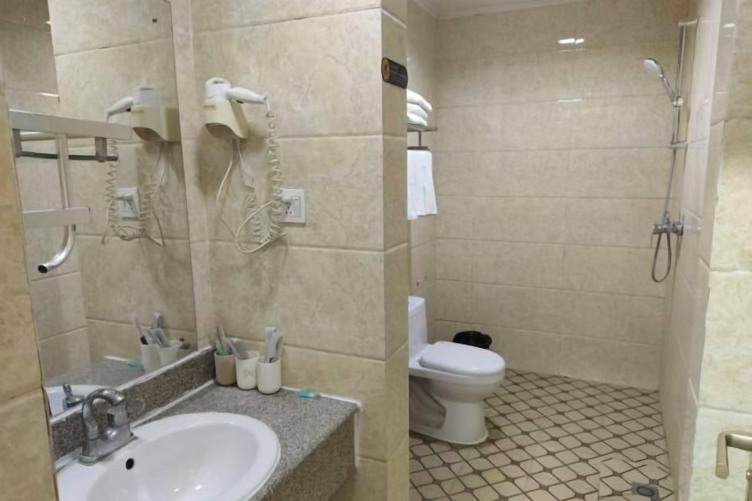 A bathroom with a sink, mirror, towel rack, and a shower area.