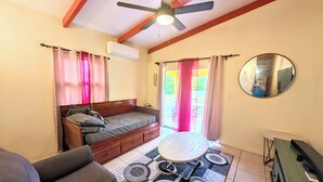 Un dormitorio con cama, sofá, una mesita y un ventilador de techo.
