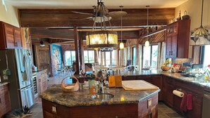 A spacious kitchen with a large island, wooden cabinets, and a farmhouse-style ceiling. - Magic Skies Surfs Up Room (Hilo)