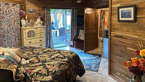 A bedroom with a bed, dresser, and a view to an outdoor area. - Magic Skies Koi Pond View Handicap Accessible Room (Hilo)