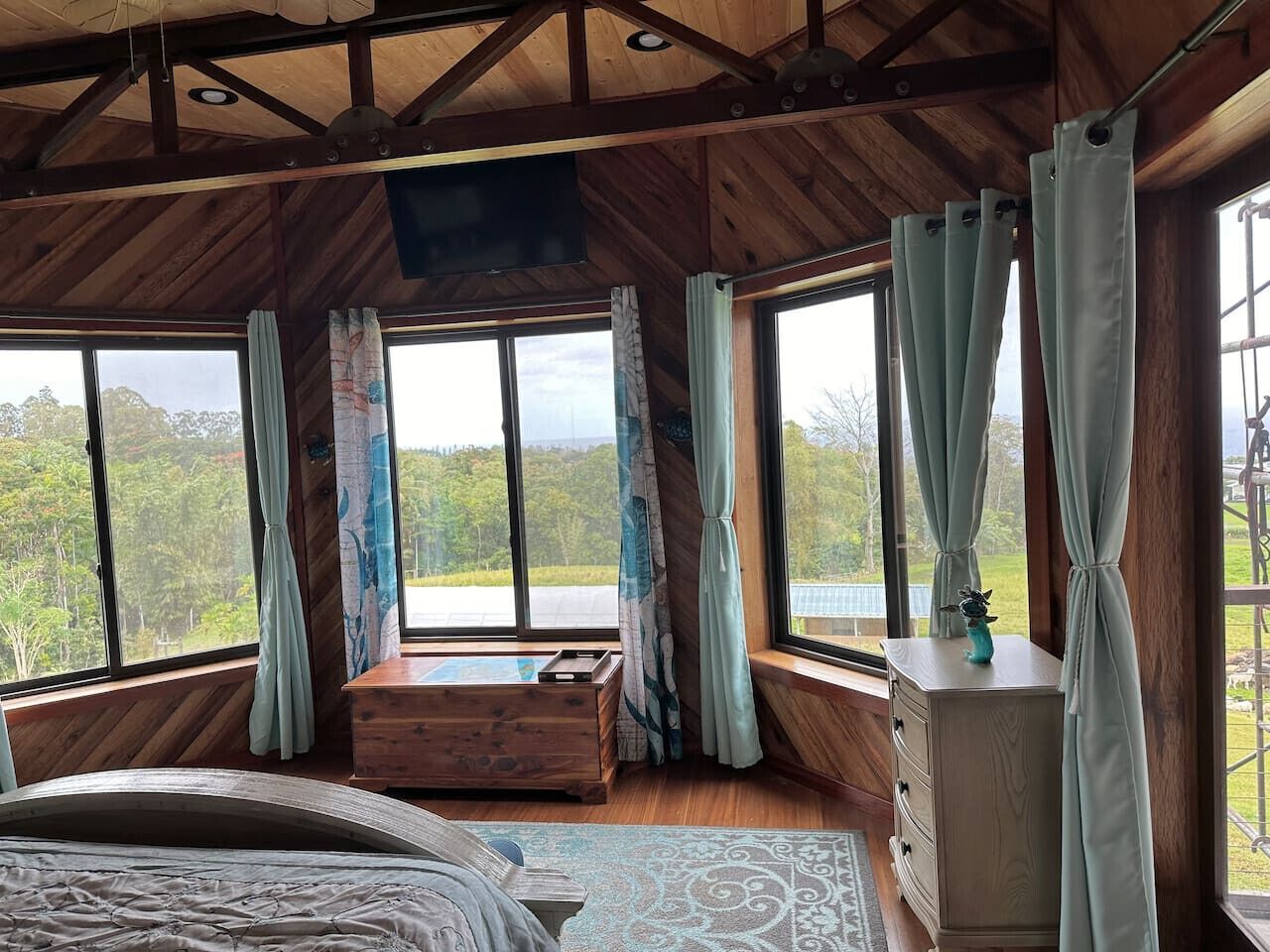 Une chambre avec un grand lit, une commode en bois et une fenêtre avec des rideaux.