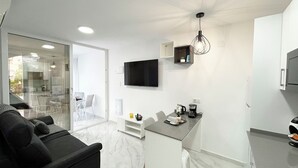 A modern kitchen with a built-in island, a flat-screen TV, and a pendant light. - Bungalow by the pool with 2 terraces, maximum capacity for 4 people (Torrevieja)