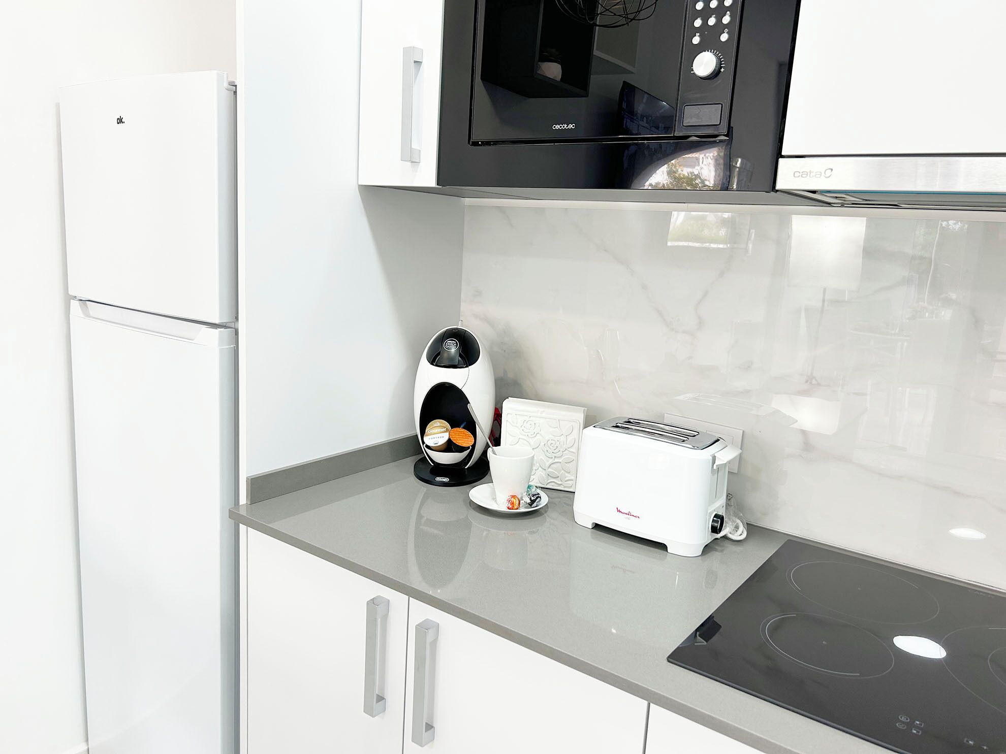 Una cocina moderna con microondas, tostadora y cafetera sobre la encimera.