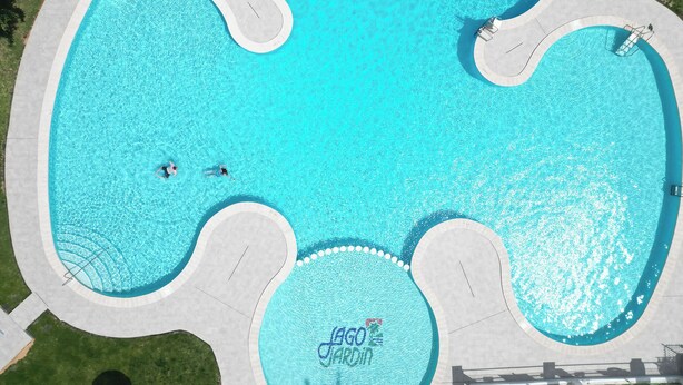 An aerial view of a uniquely shaped swimming pool with three distinct sections, surrounded by a paved walkway. - Bungalow by the pool with 2 terraces, maximum capacity for 4 people (Torrevieja)