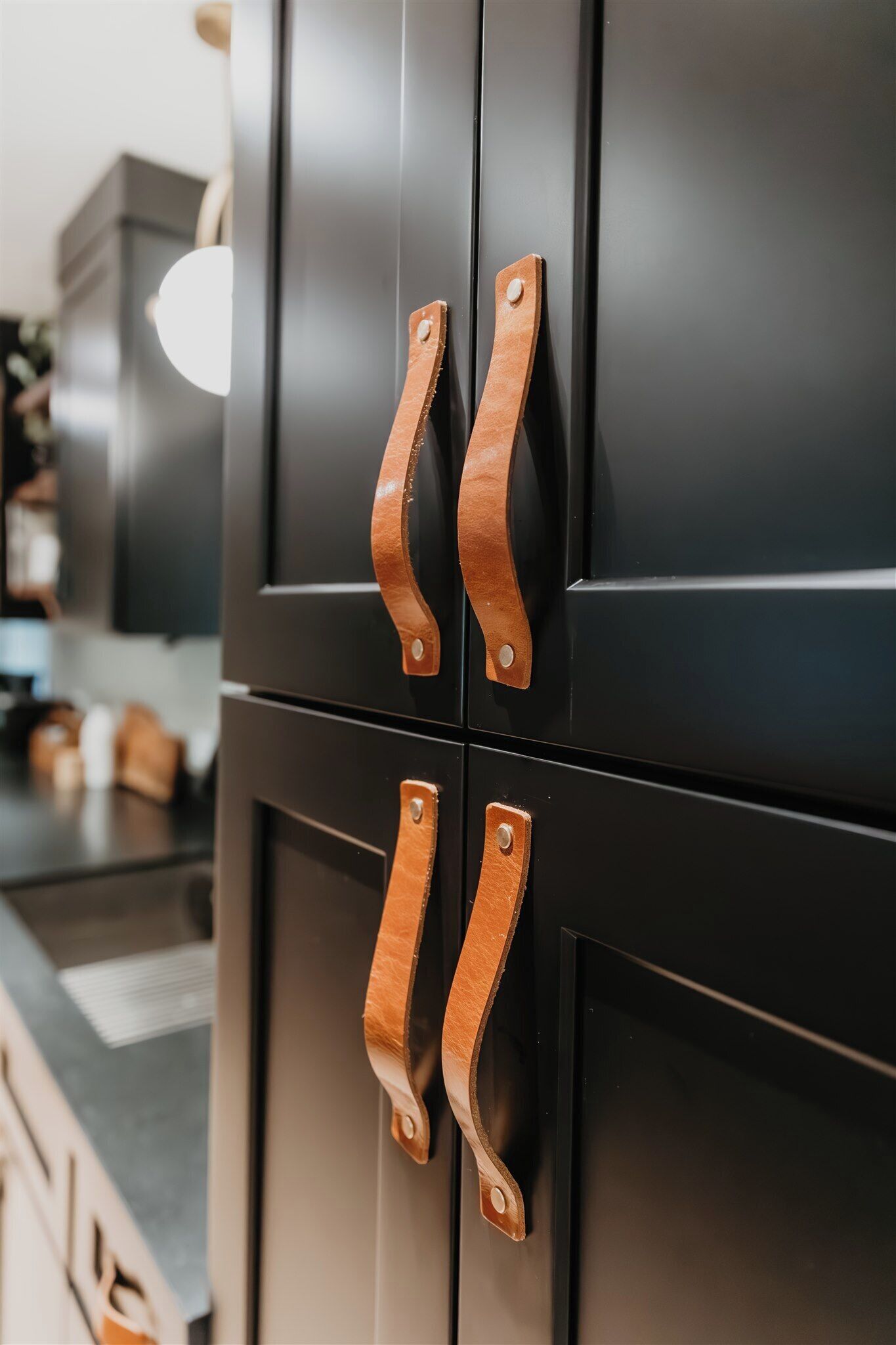 A kitchen with black cabinets and wooden handles.